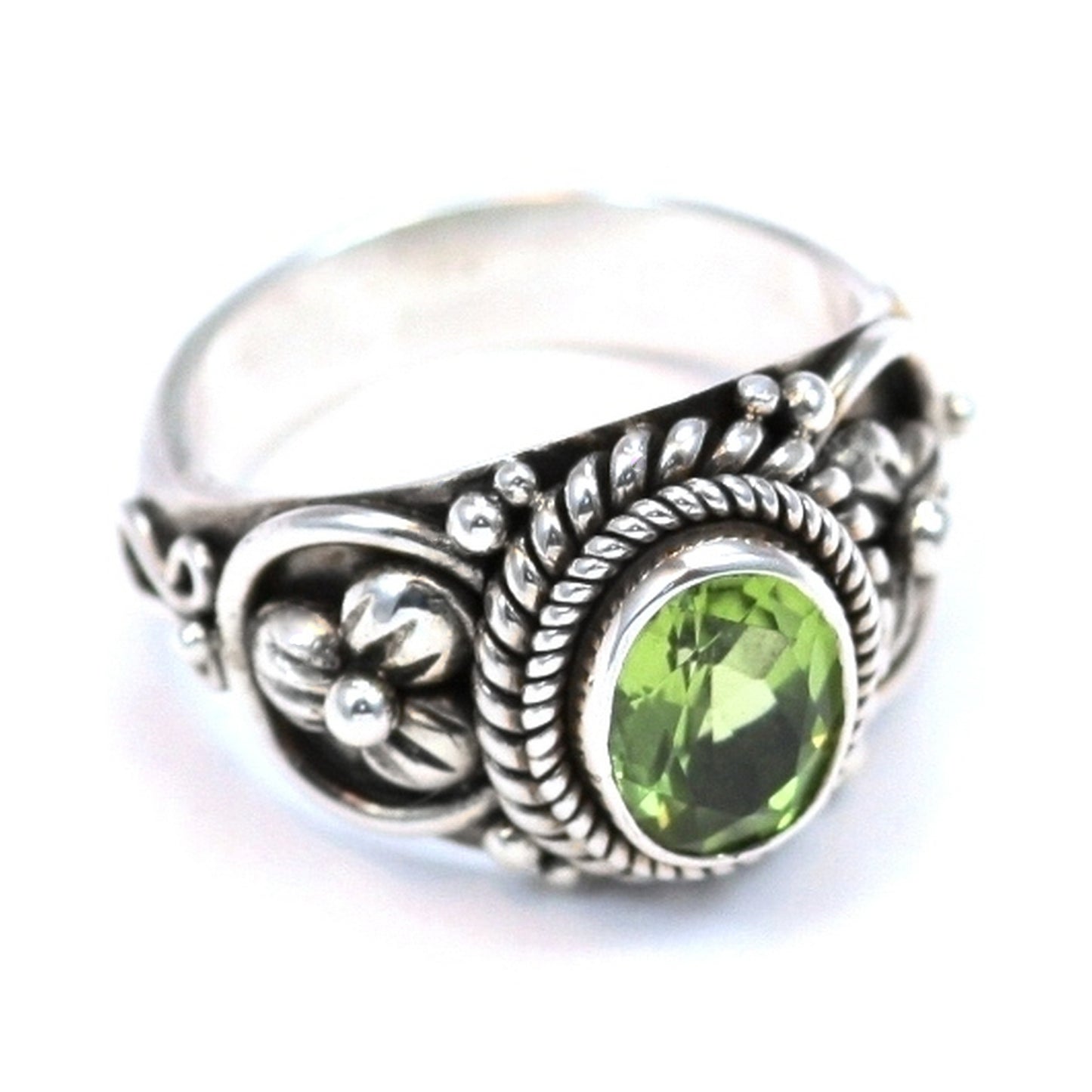 Silver ring with oval peridot gemstone and floral design.