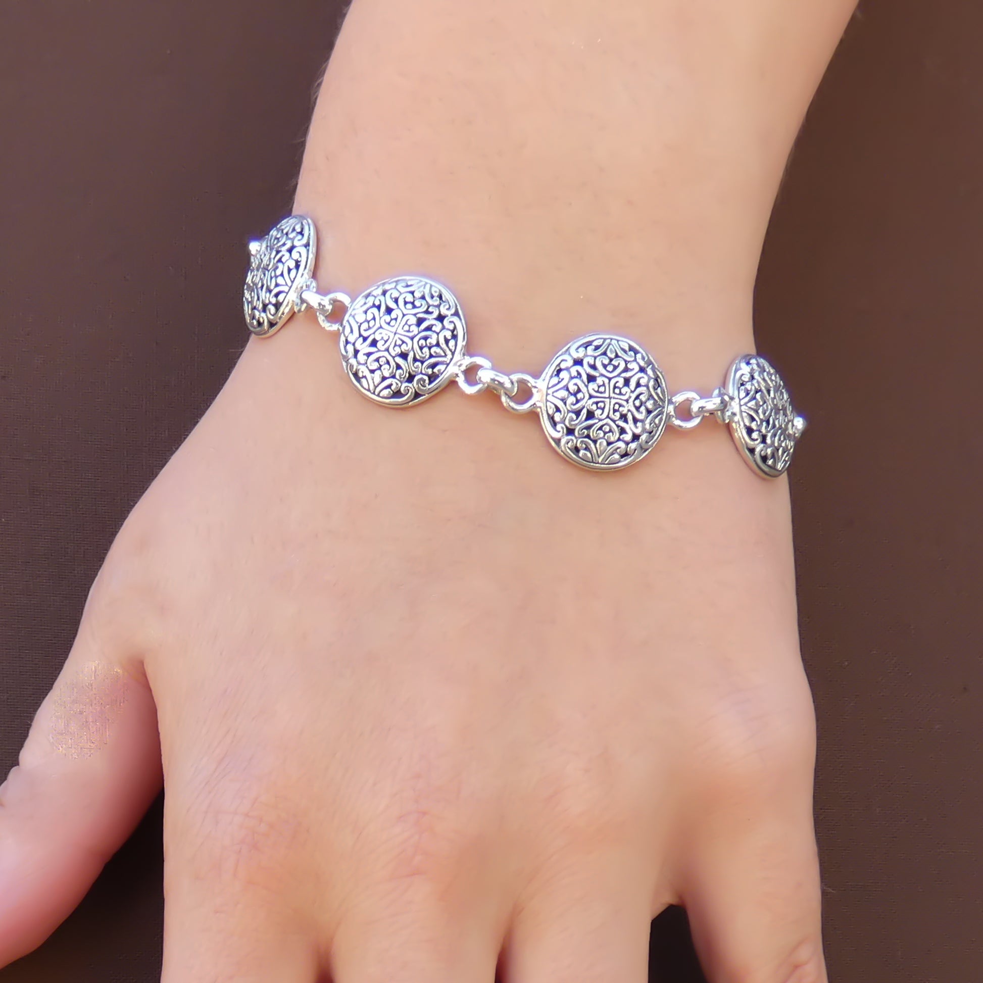 Woman wearing an ornate round link silver bracelet.