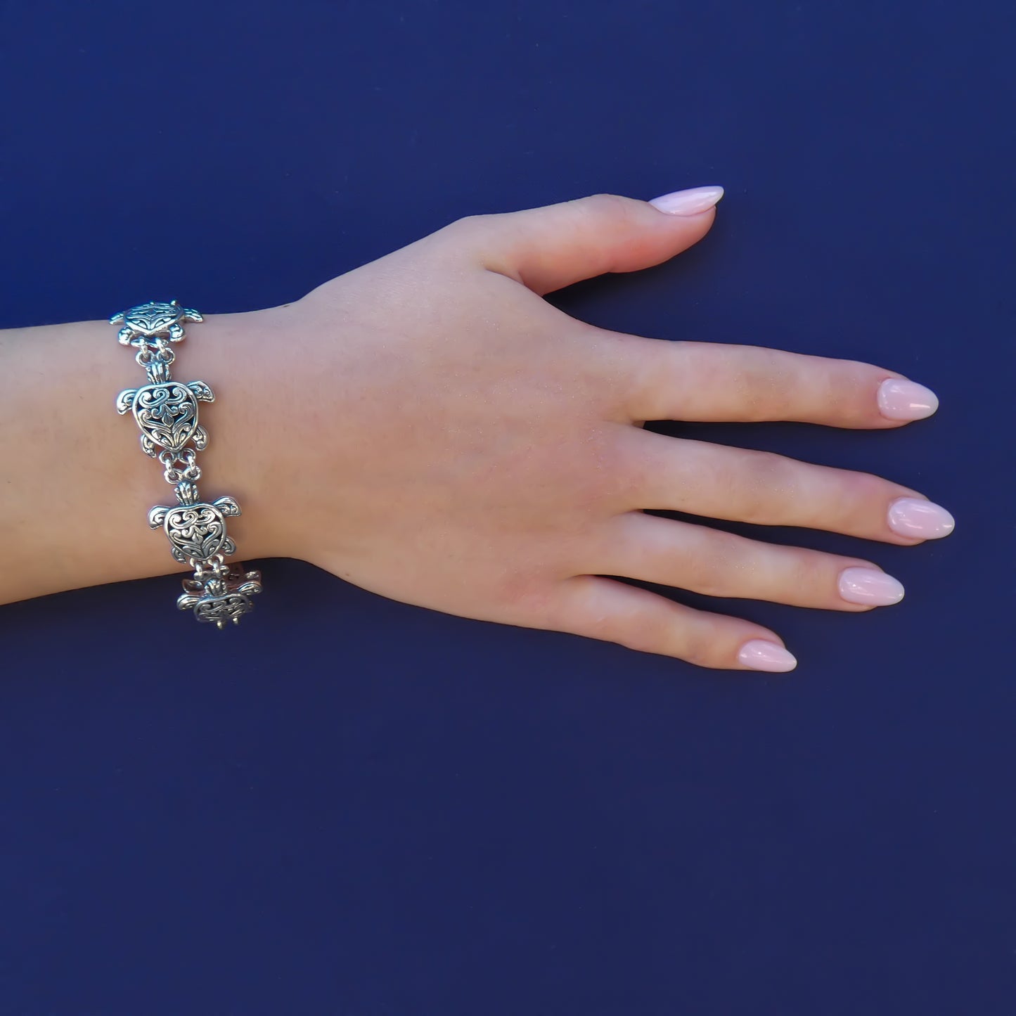 Woman wearing silver sea turtle link bracelet.
