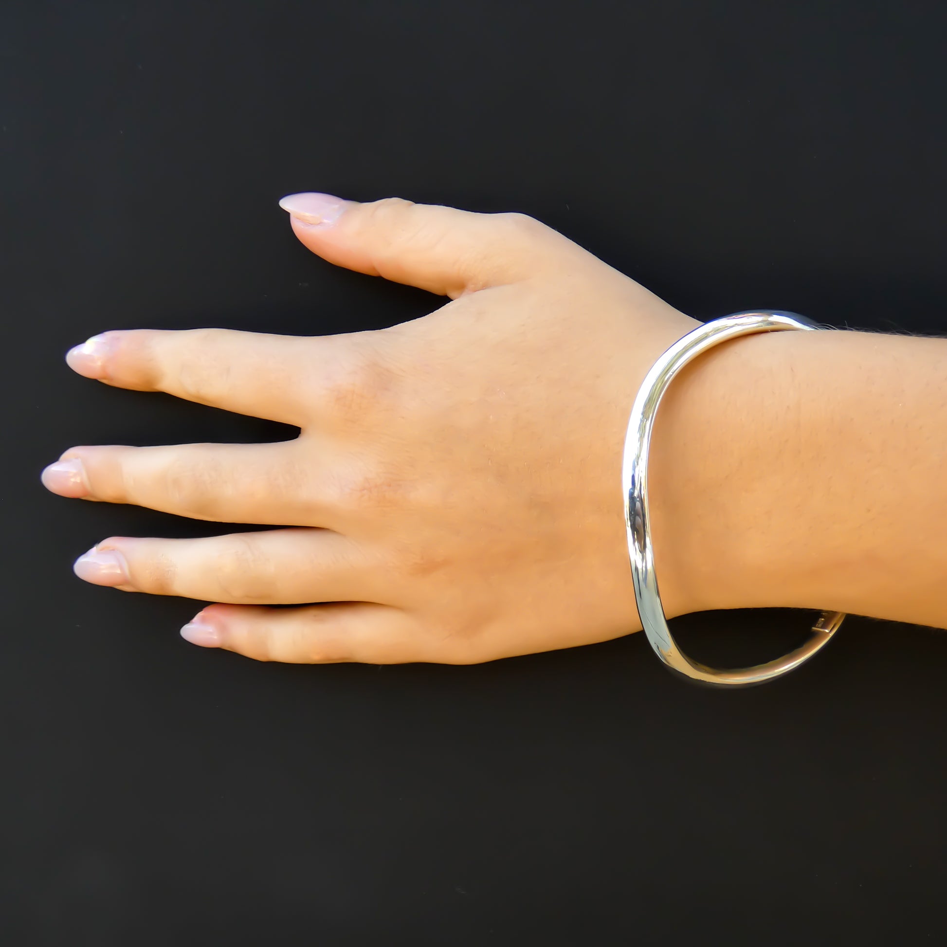 Woman wearing a wavy smooth finish bangle bracelet.