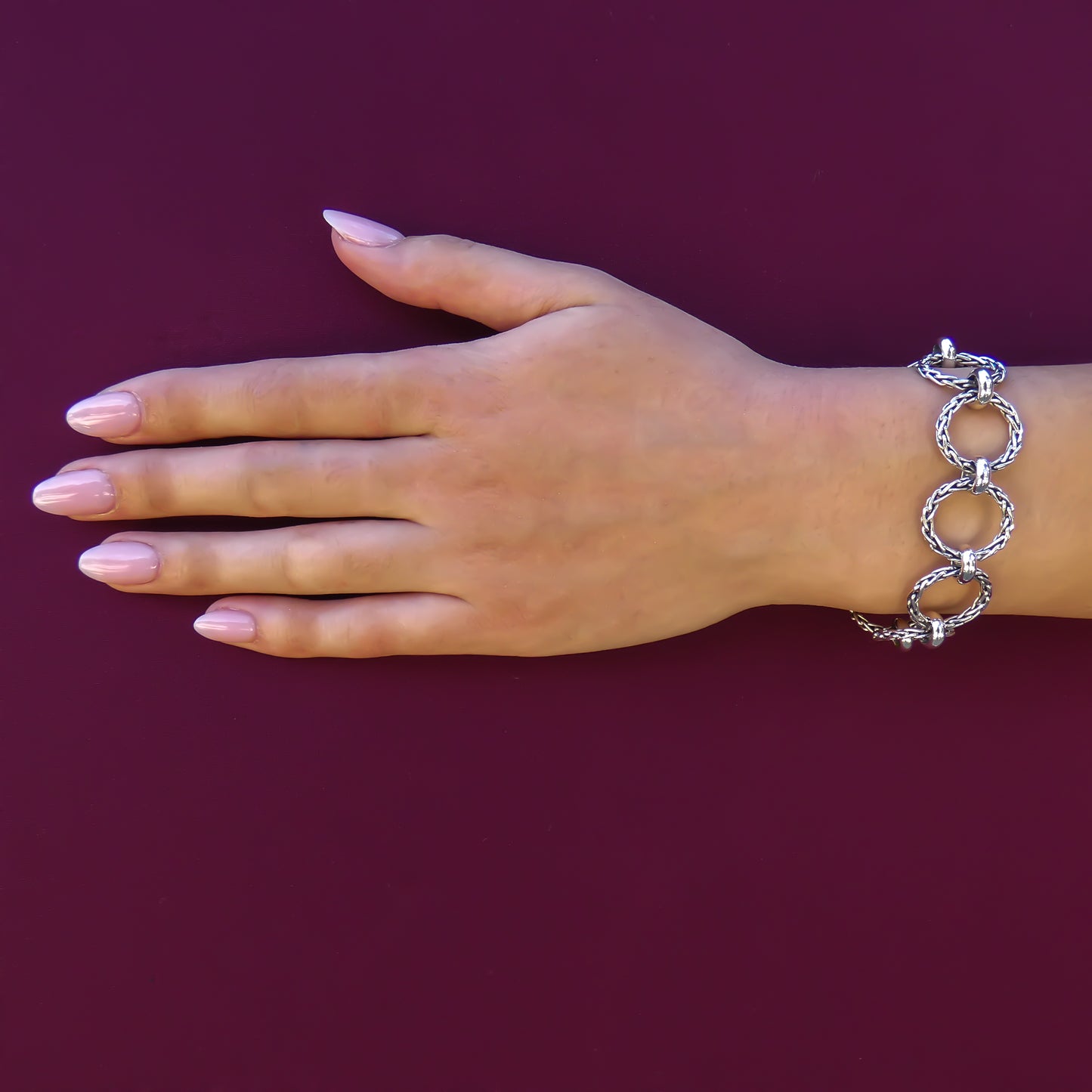 Woman wearing a silver bracelet made of wheat design ring links.