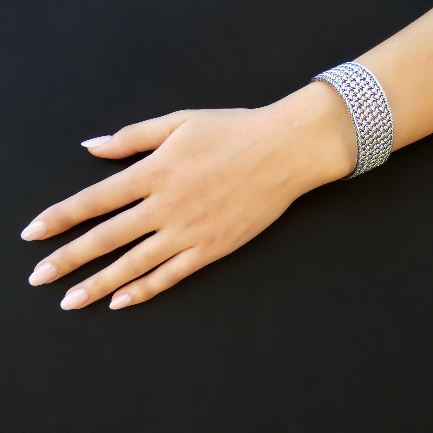 Woman wearing a wide braided silver bracelet.