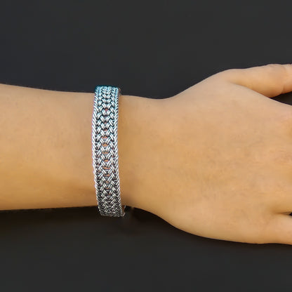 Woman wearing a flat braided silver bracelet.