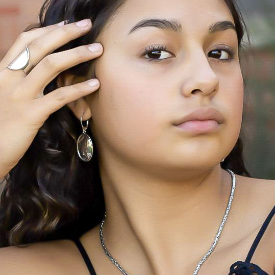 Woman wearing a silver oval hammered ring and earrings.