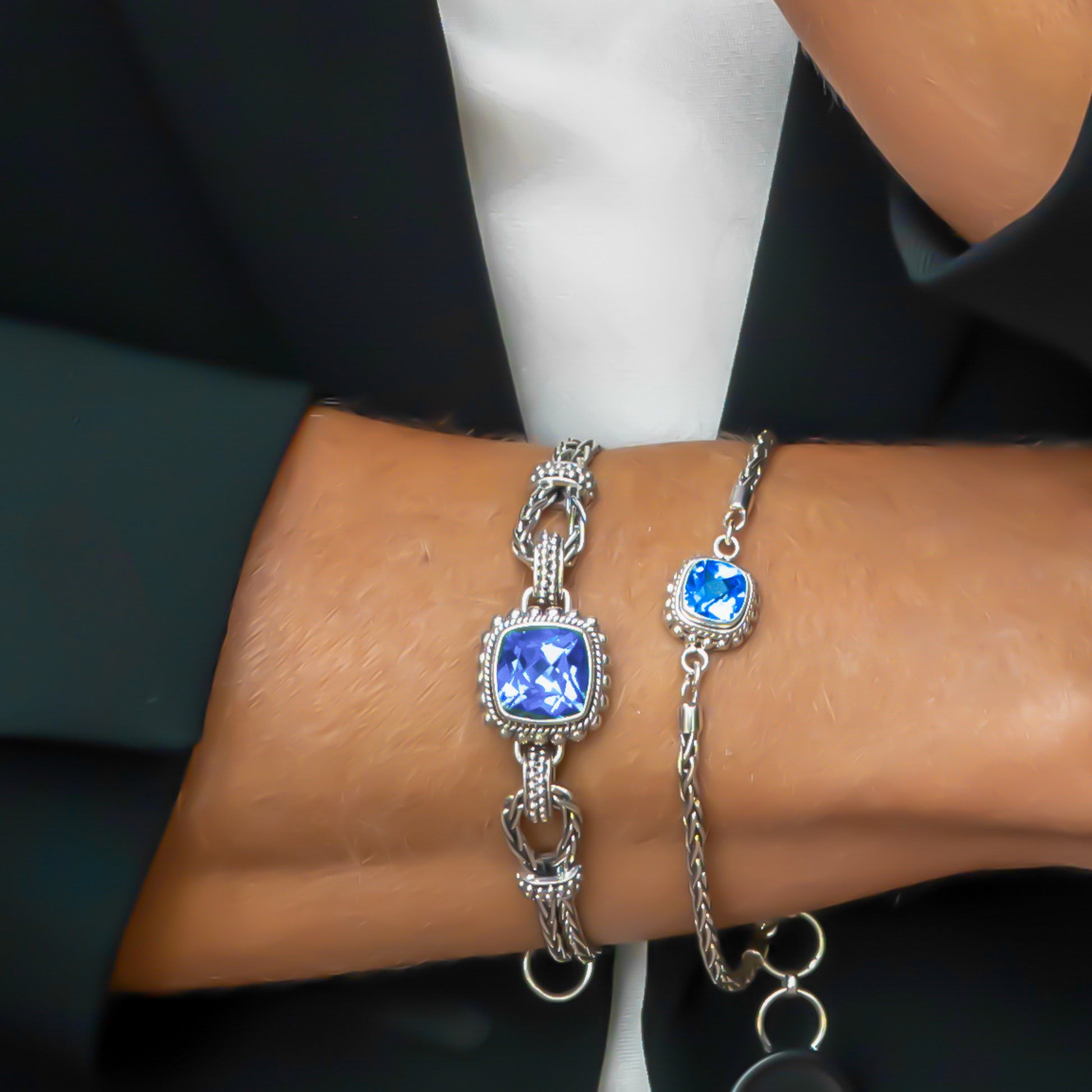 Woman's arm wearing two different sized blue topaz bracelets.