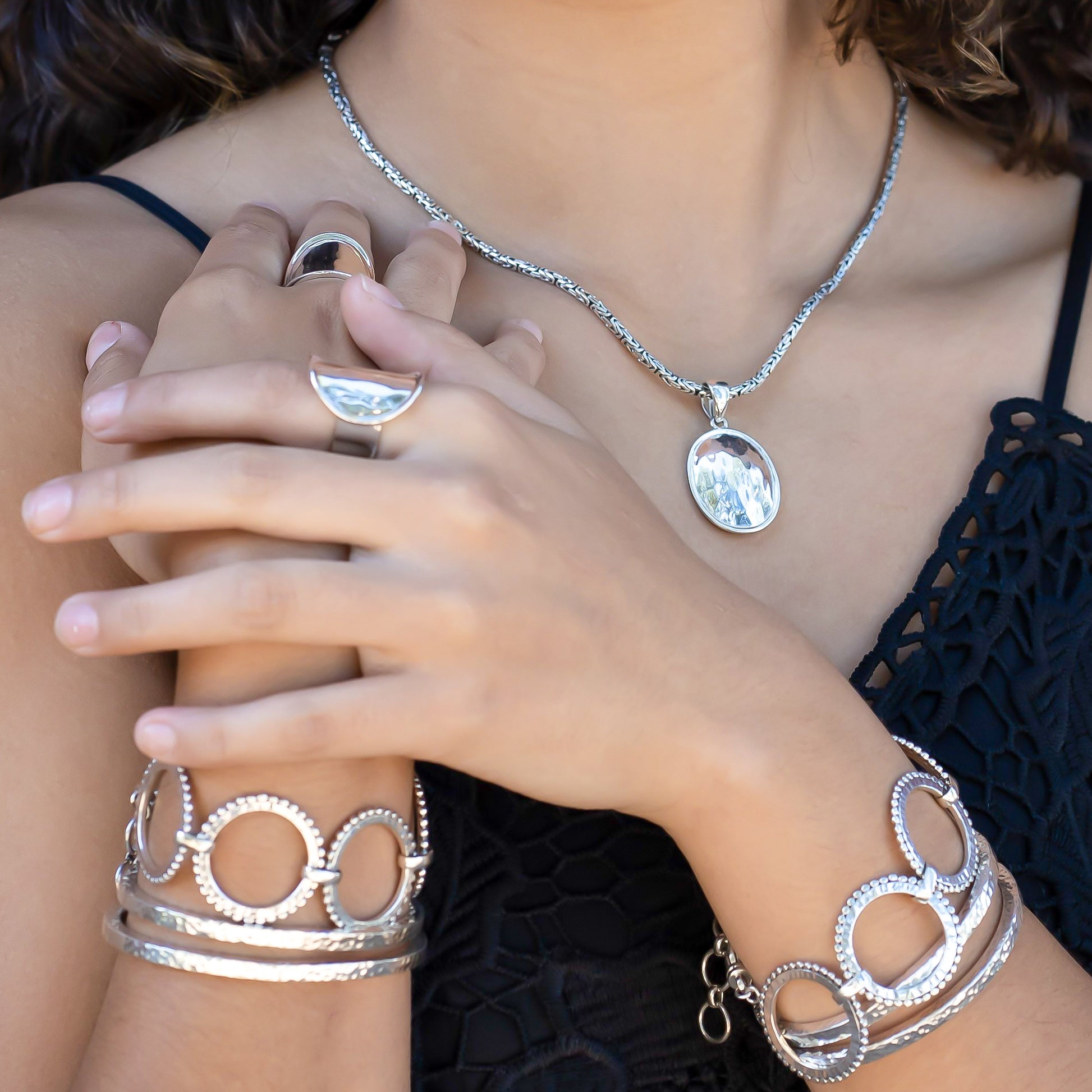 Woman wearing a variety of hammered silver jewelry.
