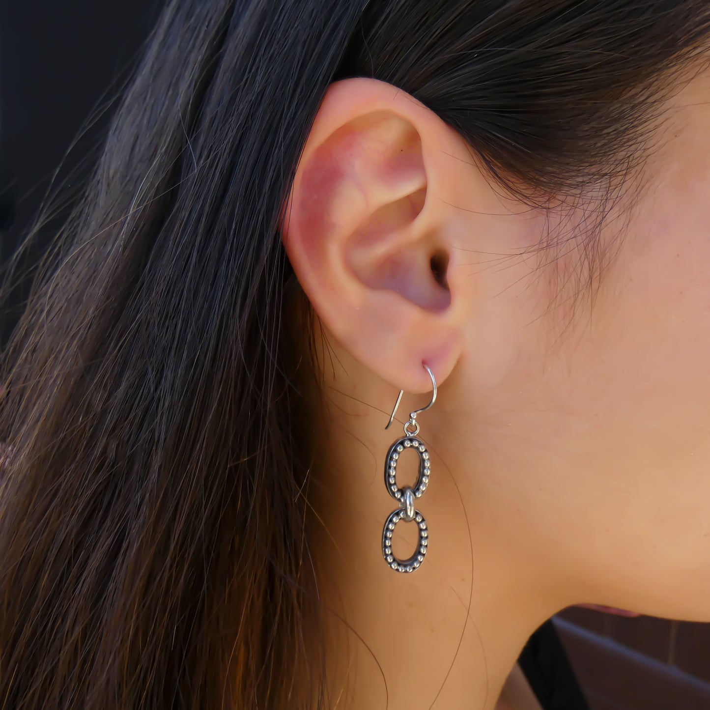 Woman wearing double oval beaded earrings.