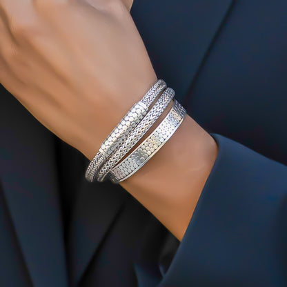 Woman wearing three different silver bracelets.