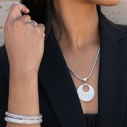 Woman wearing two silver snake chain bracelets and a silver pendant.