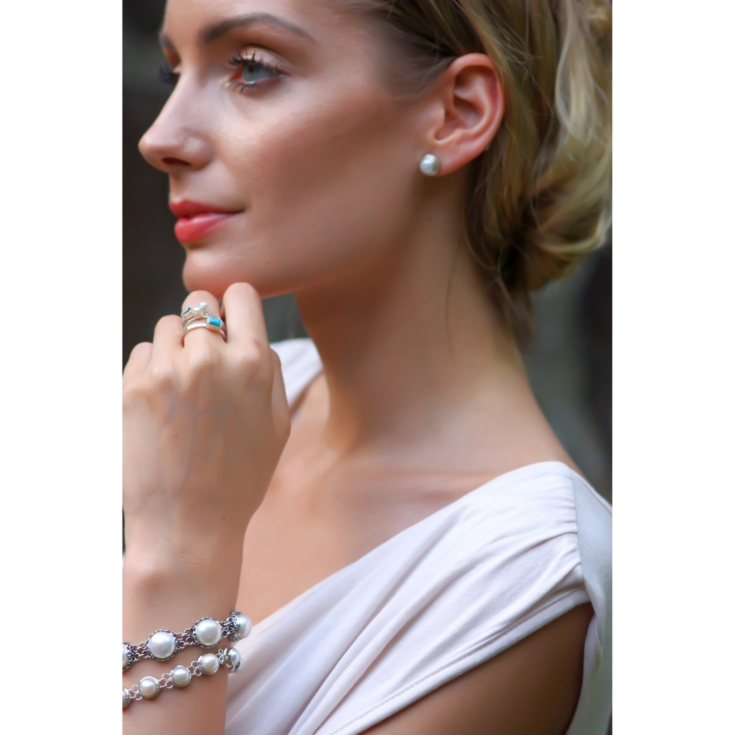 Woman wearing silver and pearl jewelry.