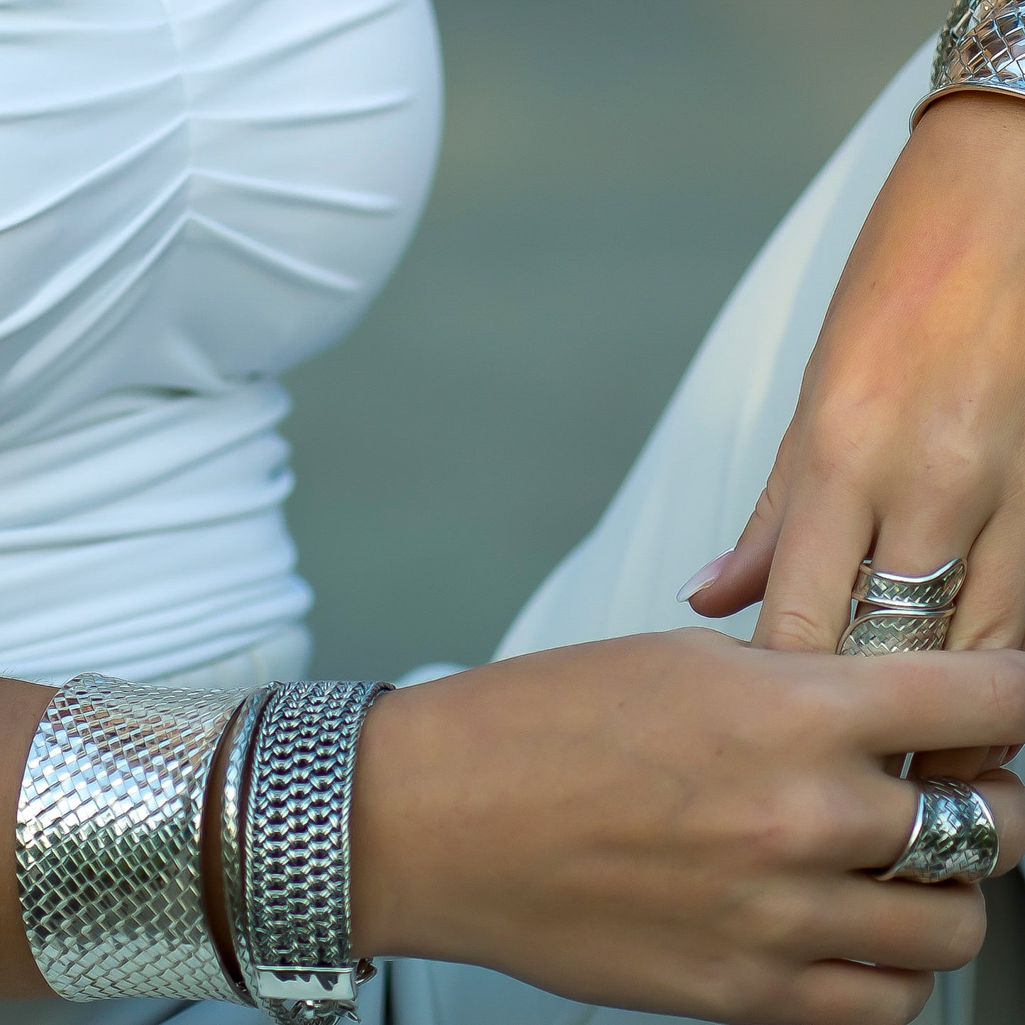 Woman wearing woven silver bracelets and rings.