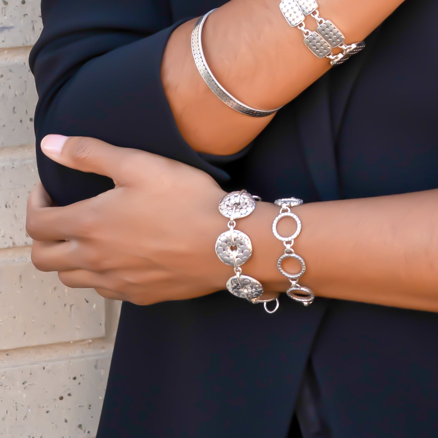 Woman wearing different silver bracelets with polished round dot shapes.