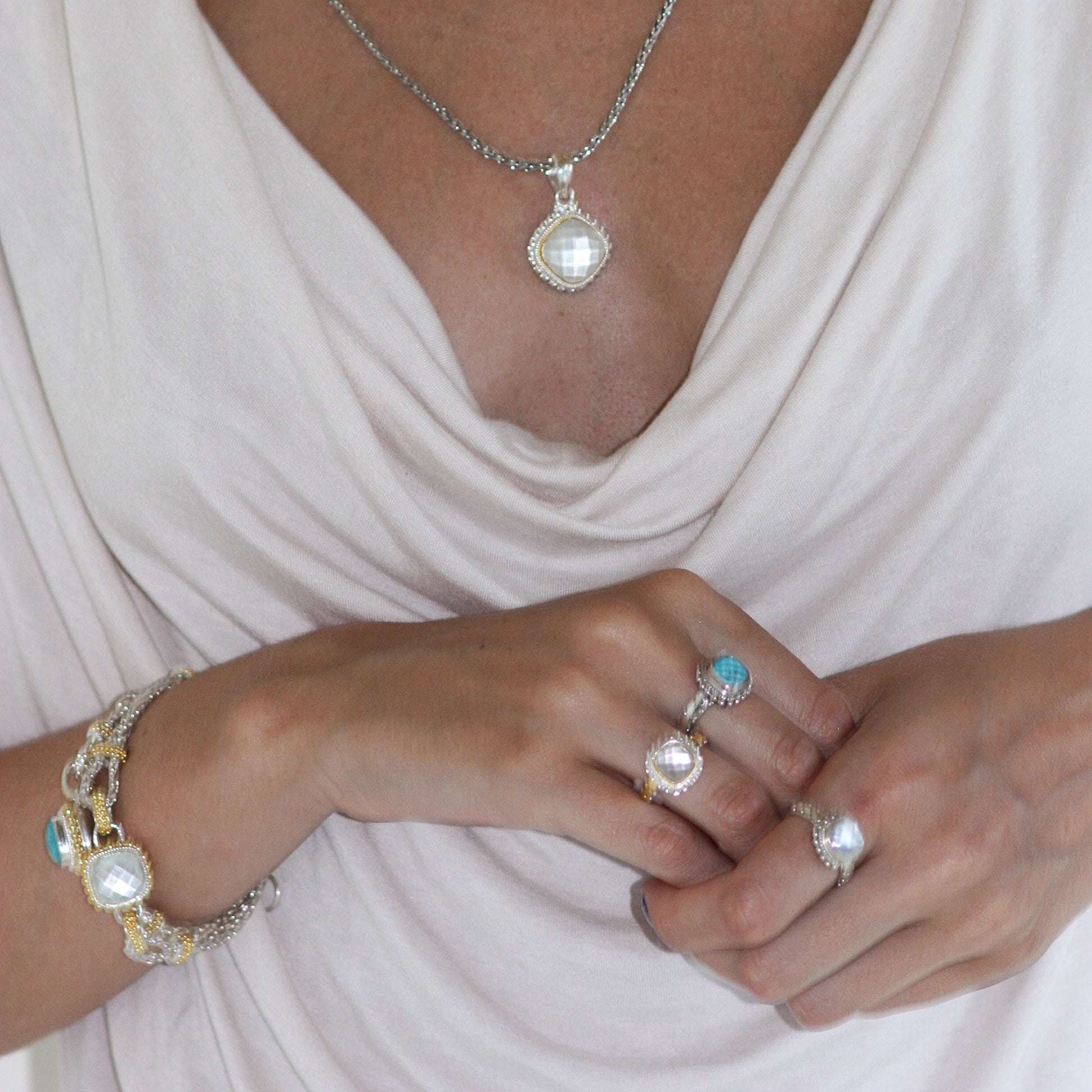 Woman wearing mother of pearl doublet bracelet, rings, and pendant.