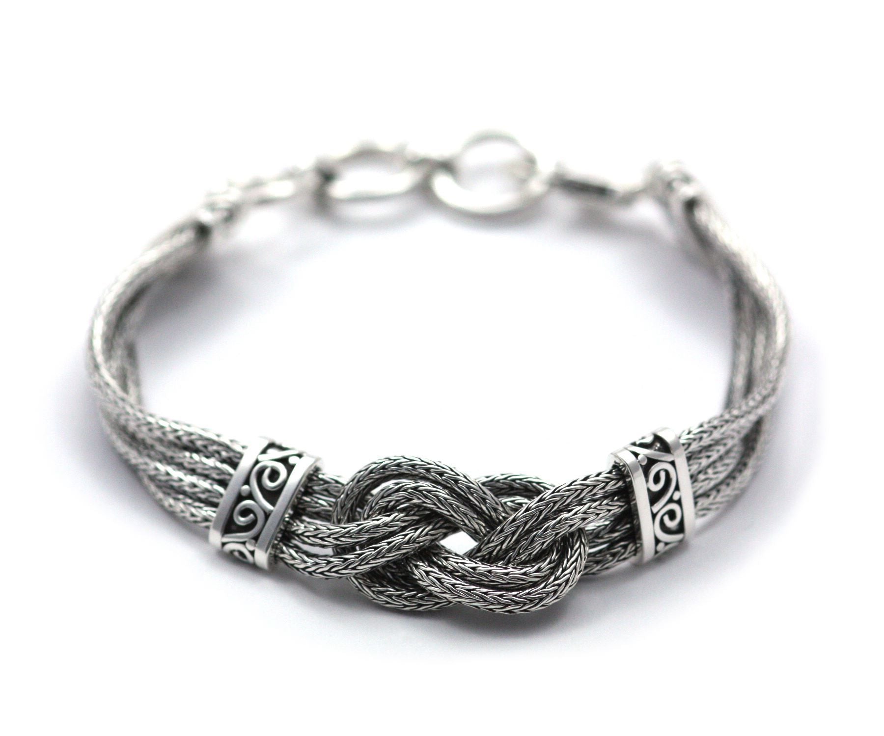Silver chain infinity knot bracelet with filigree stations on each side of the knot in the center.